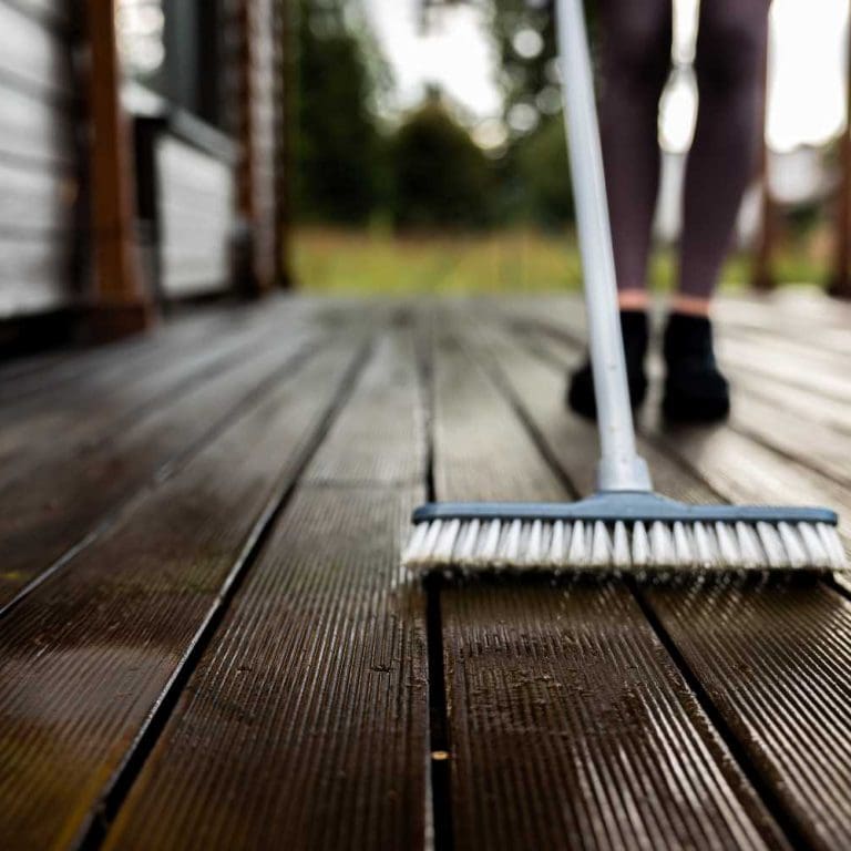 woman-washes-wooden-terrace-before-painting-it-her-modern-private-house